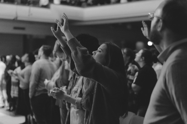 A women with her hands raised in worship at a bible conference from Moody Conferences